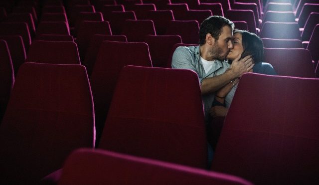 Couple kissing in an empty movie theatre