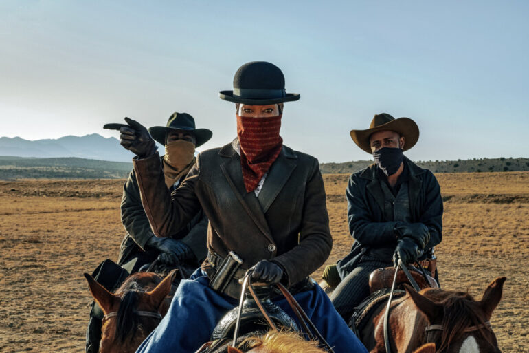Regina King, Jacobi Howard e Lakeith Stanfield montam cavalos no deserto no filme The Harder They Fall